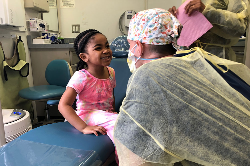 Doctor looking at a smiling child on an exam table Doctor looking at a smiling child on an exam table