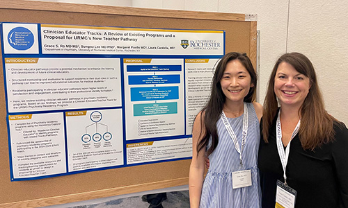 a resident and faculty member in front of a poster