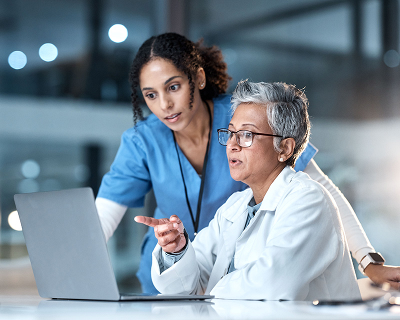 doctor and nurse talking and looking at computer