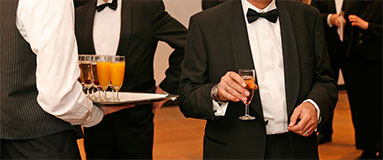 Men in suits celebrating while getting served alcohol.