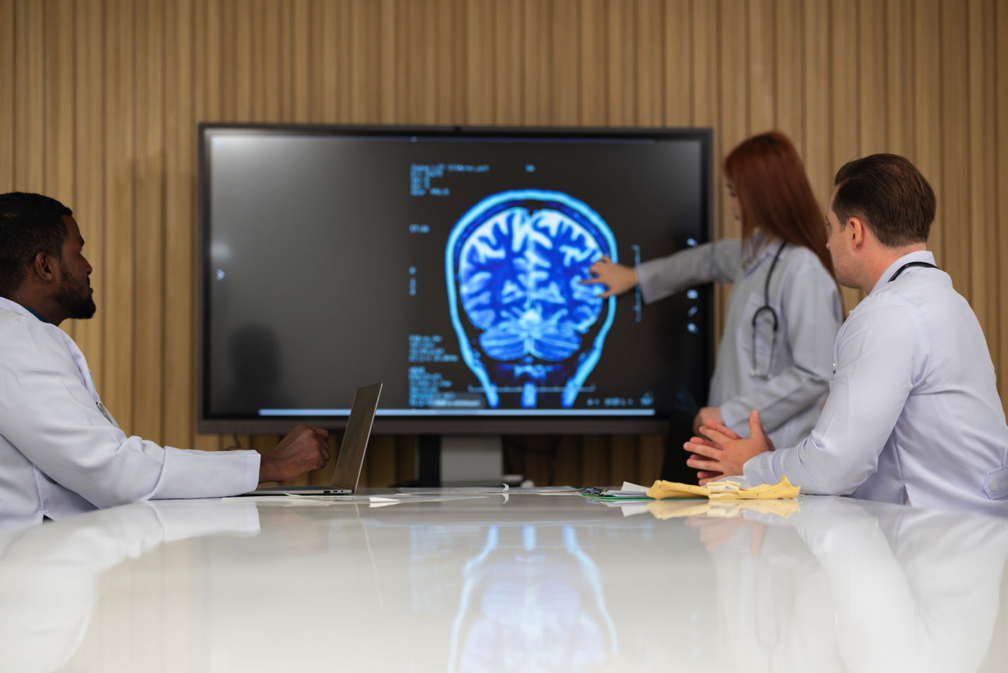 Group of doctors collaborating while reviewing brain scans.